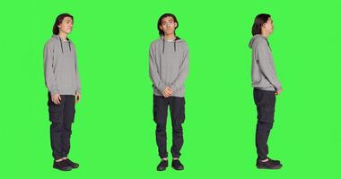 Young model doing no sign on camera, expressing negativity and disagreement over blank greenscreen backdrop. Asian person being displeased and disapproving with something, denial. photo