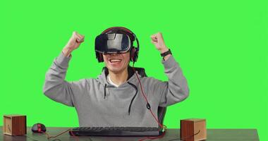 POV of gamer enjoying vr games sitting at workstation over greenscreen background, playing online with colleagues enjoying rpg gameplay. Young guy using virtual reality glasses. photo