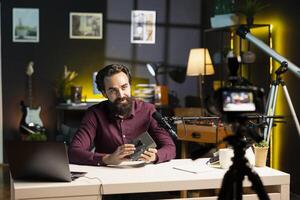 Tech guru presenting V mount battery, filming technology review using professional camera and mic. Media star showcasing charging device specs, recording with specialized equipment photo