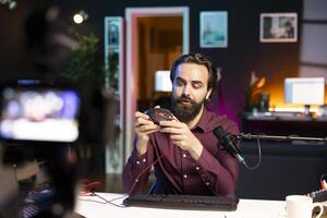 Tech guru promoting wired gaming mouse from sponsor to subscribers. Content creator paid by brand to showcase computer peripheral device, recording with professional camera and mic photo