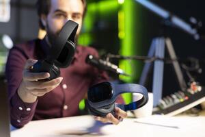 Close up shot of newly launched wireless headphones reviewed by man comparing features with older models. Focus listening devices analyzed by technology internet show host in blurry background photo