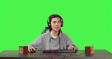 POV of player competing at games on computer while speaking on headphones to his friends, playing interactive combat challenge at desk. Asian gamer having fun with his free time. photo