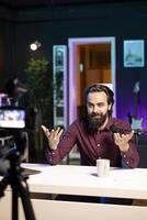 Media star talking in professional microphone in studio at night, filming internet production. Content creator uses quality mic and camera to record vlog and speak to audience photo