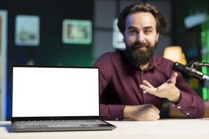 Close up shot of mockup laptop being assessed by cheerful tech expert talking about parts used inside. Focus on isolated screen notebook reviewed by man in blurry background for technology channel photo