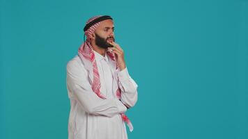 Muslim person looks contemplative and thinking about innovative solutions, acting interested and trying to find answer. Young guy with headscarf being thoughtful and puzzled on camera. photo