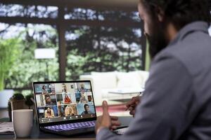 Chief executive director discusses with creditors via videocall from his luxury forest villa, engaged in web online connection for briefing meeting. Company owner presents global expansion ideas. photo