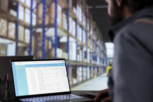 Cargo engineer reviewing checklist for order distribution in depot, creating receipts for merchandise. Warehouse employee dealing with dispatch notes for supply chain management, storage room. photo