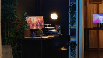 Work desk with computer and house plants in empty house interior with warm lighting. Living room illuminated by neon lights with 3D rendered animations running on powerful PC monitors photo