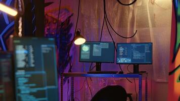 Software interface on computer screen showing programming code used for making malware in empty warehouse with graffiti sprayed on walls. Hacking script running on PC monitors in underground base photo