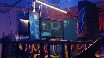 Jib down shot of abandoned basement with graffiti drawings on walls and high tech computer equipment left open running code. Underground hideout used as base of operations by hackers photo
