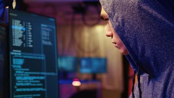 Extreme close up on hacker in graffiti painted hideout focused on developing spyware software, using it to gather information from users computers without their knowledge photo