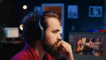 producer adds sound effects to film montage, working in studio, close up panning shot. Videographer using headphones to test and improve audio quality using specialized software on computer photo