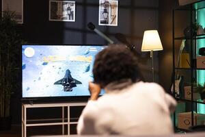 Man playing videogames on gaming console, celebrating victory after defeating all enemies. Gamer excited after winning internet esports game match on smart TV display, rejoicing photo