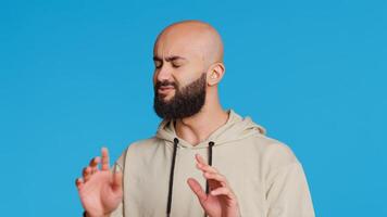 Arab male model doing no symbol on blue backdrop, showing his rejection and denial in studio. Middle eastern guy expressing refusal with a negative gesture, serious man. Camera 2. photo