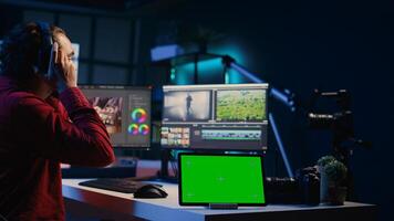 Chroma key tablet next to editor using editing software to upgrade footage. Isolated screen device near freelancer videographer finishing project in apartment studio photo