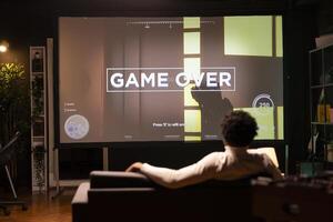 Man seeing livestream footage on ultrawide smart TV display from content creator losing videogame. African american gamer sitting at home and seeing pro streamer being defeated in esports competition photo