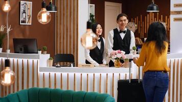 Front desk team greeting guest at five star hotel reception, welcoming person and ensuring easy check in procedure. Woman client entering lobby with luggage, hospitality industry. photo