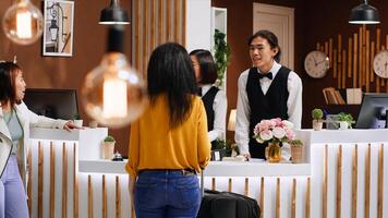 Hotel guests using service bell for assistance at front desk, calling for employees team to help with check in procedure upon their arrival. Two friends on holiday requesting support from staff. photo
