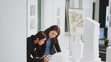 Two architects measuring building scale on blueprint, working together to create sketch of home layout. Team of developers drawing lines and elements on engineering drafts in agency office. photo