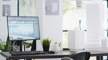 Creative agency office empty desk with pc running cad software, manufacturing floor plans and blueprints placed on design table. Architectural coworking space filled with modern development tools. photo