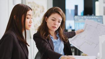 Designers analyze 3D building models to generate specifications, examining maquettes to develop production blueprints. Team of architects focus on industrial drafts in shared workspace location. photo