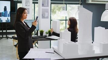 Agency engineer using graphic software on smartphone, trying to find out scale measurements for future construction project. Architect scanning 3d building model on phone app, remodeling concept. photo