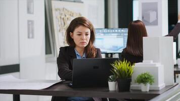 Architect studying property layout on laptop to create blueprint, working on remodeling project at real estate agency office. Expert developing draft with scales and measurements to remodel space. photo