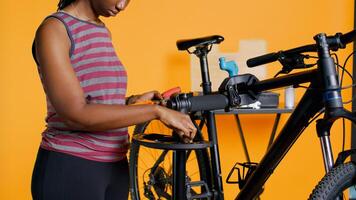 Close up shot of worker preparing work tools before starting refurbishing malfunctioning bicycle, studio background. Expert arranging screwdriver, pliers and hex wrench on equipment support, camera B photo