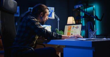 Man concerned about statistical data financial graphs on laptop screen while researching data for company project. Freelancer unhappy about business graphic figures, feeling stressed, camera B photo