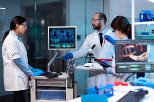 Research scientists working on monitor analyzing virus with chemistry team. Chemists in pharmaceutical lab examining sample for medical experiment with technology for medicine industry. photo