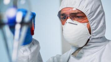 Close up of chemist holding blood sample wearing coverall analysing virus evolution in laboratory. Doctor working with various bacteria, tissue, pharmaceutical research for antibiotics against covid19 photo