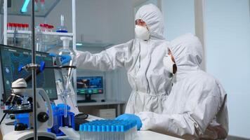 Scientist team in prorection suit arguing in front of pc looking at virus development in equipped laboratory.Team of scientists analysing vaccine evolution using high tech for researching treatment photo