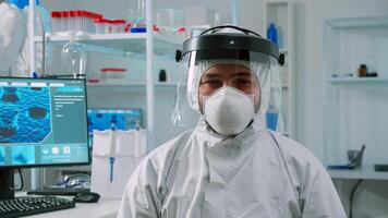 Overworked chemist sitting in modern equipped lab wearing coverall looking tired at camera. Team of doctors examining virus evolution using high tech and chemistry tools for vaccine development photo