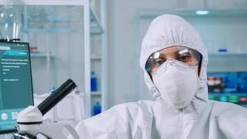 Professional woman scientist in protection suit looking tired at camera in equipped lab. Overworked team examining virus evolution using high tech and tools for scientific research vaccine development photo