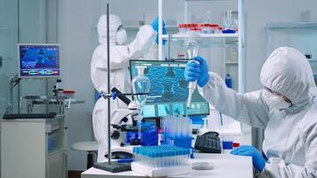 Scientist wearing coverall in equipped medical laboratory examining drug discovery with micropipette. Biochemists analysing virus evolution using high tech researching vaccine against covid19 photo
