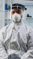 Portrait of experienced scientist man in coverall smiling at camera wearing protection mask in equipped lab. Examining virus evolution using high tech and chemistry tools for vaccine development. photo