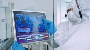 Chemist in ppe suit explainig to doctor vaccine development in modern equipped laboratory pointing on computer desktop. Team of doctors examining virus evolution using high tech researching diagnosis photo