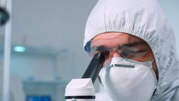 Close up of scientist man in medical industry carrying out genetic analysis using microscope. Chemist researcher in sterile lab doing experiments for medical industry using modern technology photo