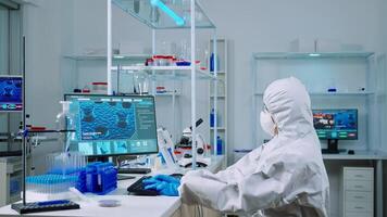 Chemist typing on pc and coworker analysing microscope slides in equipped laboratory. Team of scientists examining vaccine evolution using high tech for researching treatment against covid19 virus photo