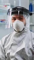 Tired doctor in protection suit against covid-19 looking exhausted at camera in equipped lab. Team of scientists examining virus evolution using high tech for scientific research, vaccine development. photo