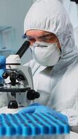 Biological scientist in coverall using microscope doing research for new vaccine in pharmaceutical labolatory. Coworkers examining virus evolution using high tech researching diagnosis against covid19 photo