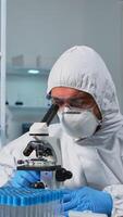 Biologist doctor in coverall checking DNA sample typing on pc in modern equipped laboratory. Team examining vaccine evolution in medical lab using high tech and chemistry tools for scientific research photo