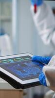 Back view of scientist in coverall analyzing virus evolution looking on digital tablet. Team of microbiologists conducting vaccine development using high tech for researching treatment against covid19 photo