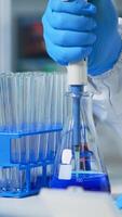 Close up of researcher testing liquid sample using micropipette for new treatment medical laboratory. Team of doctors examining virus evolution using high tech for vaccine development against covid19 photo
