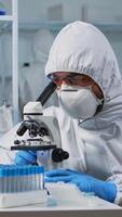 Close up of scientist looking through a microscope wearing ppe suit in equipped lab. Team examining virus evolution using high tech for scientific research of vaccine development against covid19. photo