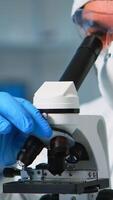 Close up of chemist doctor analysing virus using microscope in ppe suit. Team of scientists examining vaccine evolution using high tech for scientific research of treatment development against covid19 photo