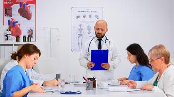 Medical staff listening to lecture, asking questions and taking notes at medical conference sitting in hospital meeting room. Group of physicians talking about symptoms of disease in clinic office photo