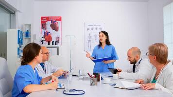 Attentive medical team discussing medicine problems, doctors with tablet pc and clipboards working in meeting hospital office. Brainstorming ideas, physicians diagnosis using modern technology photo