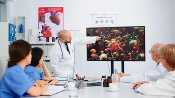 Specialist medic explaining virus development on digital screen in front of coworkers pointing on monitor in hospital office during brainstorming. Team of physicians analysing diagnosis of patients photo