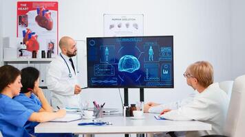 Medical worker presenting report on digital screen about internal human brain in front of colleagues pointing on monitor in hospital office during brainstorming. Team analysing diagnosis of patients photo